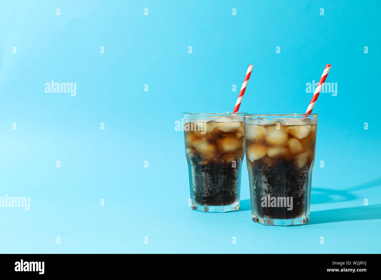 I bicchieri con il freddo cola di tubuli e su sfondo blu, spazio per il testo Foto Stock