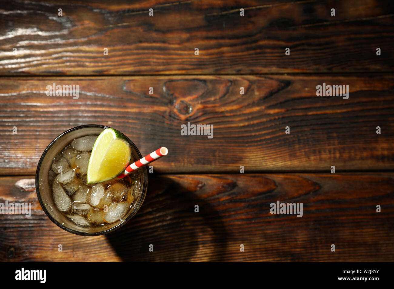 Bicchiere con ghiaccio cola e calce fetta su sfondo di legno Foto Stock