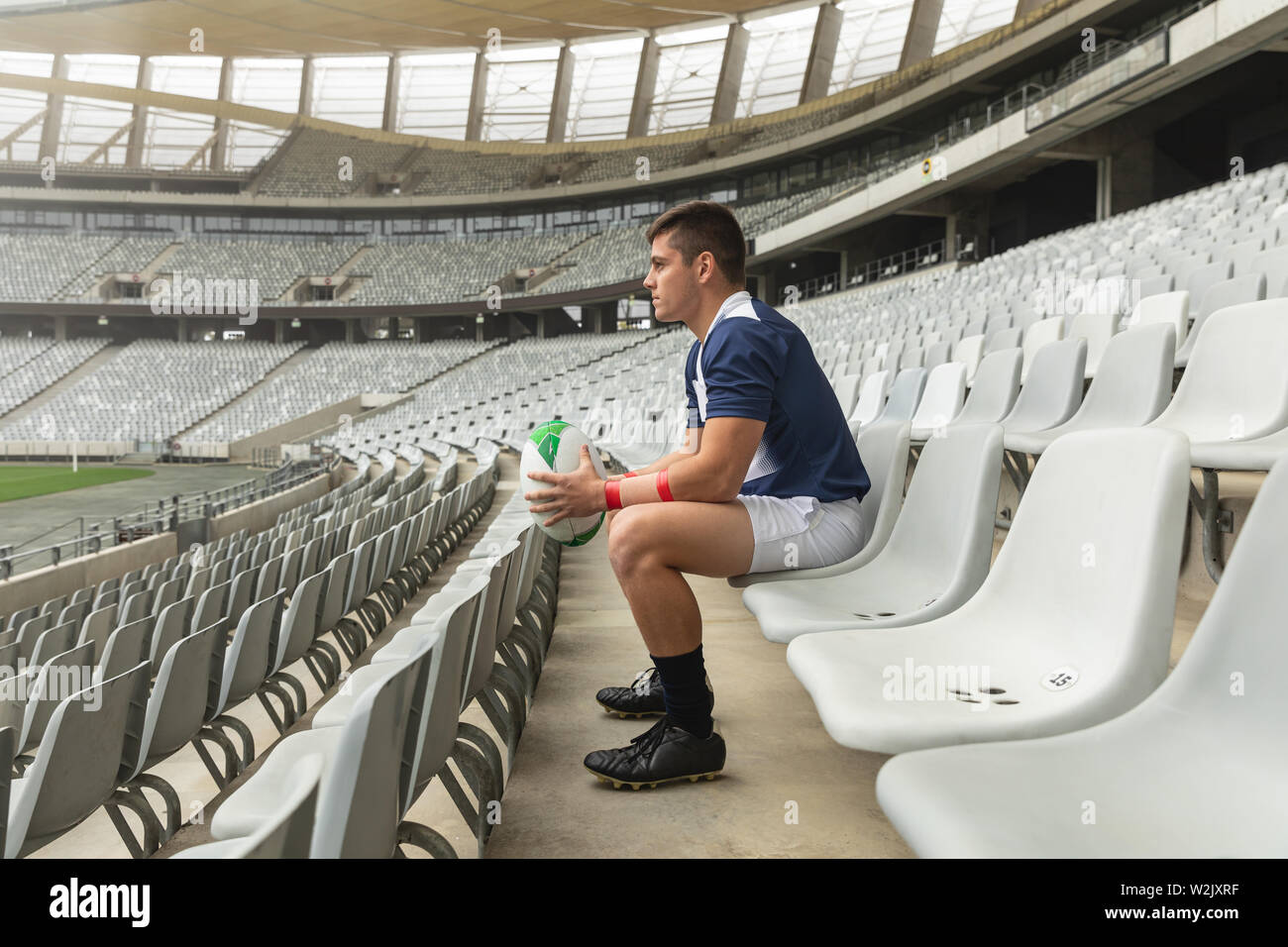 Maschio caucasico rugby giocatore seduto con palla da rugby in stadium Foto Stock