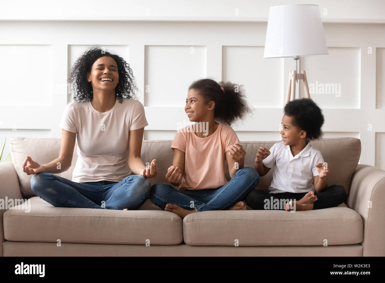 Felice di ridere singola nero mom meditando con i bambini a casa Foto Stock