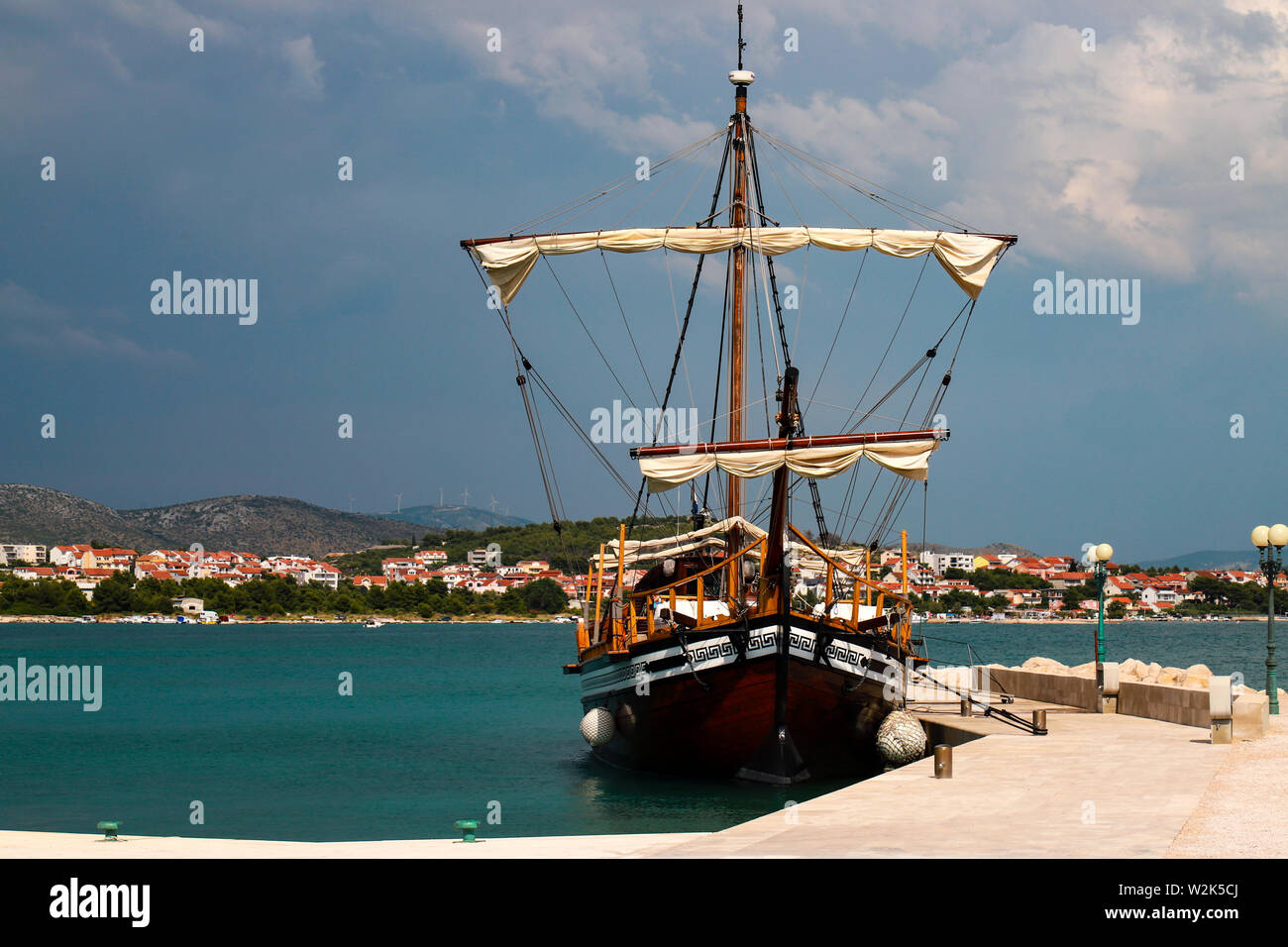 Bellissimo legno marrone yacht vicino al molo con lanterne in mare azzurro e limpido, pittoresco nuvole di Sibenik, Croazia. Viaggi croato, mare il resto e Foto Stock
