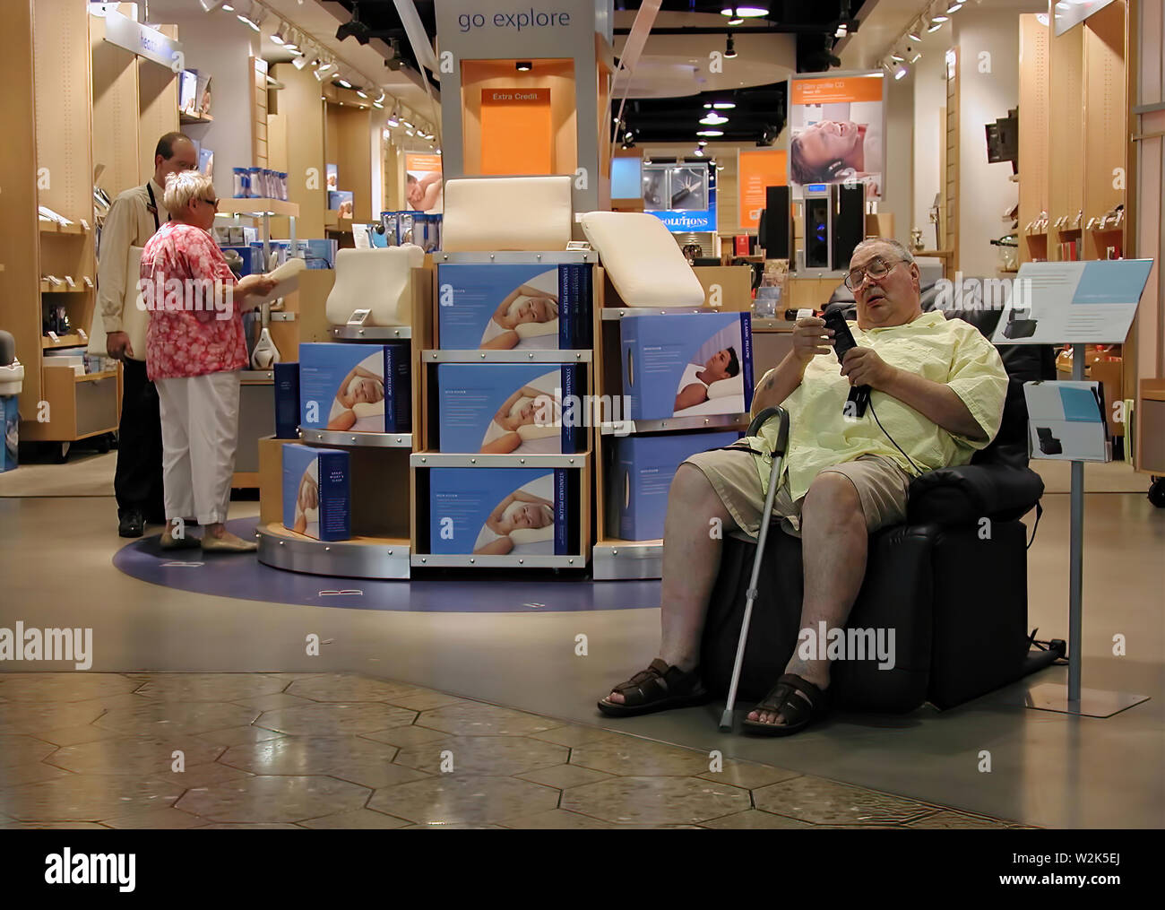 West Hartford, CT, Stati Uniti d'America. Aug 2016. Un uomo anziano al centro commerciale il controllo automatizzato lo schienale massaggiante mentre l altra metà della chat con un rappresentante. Foto Stock