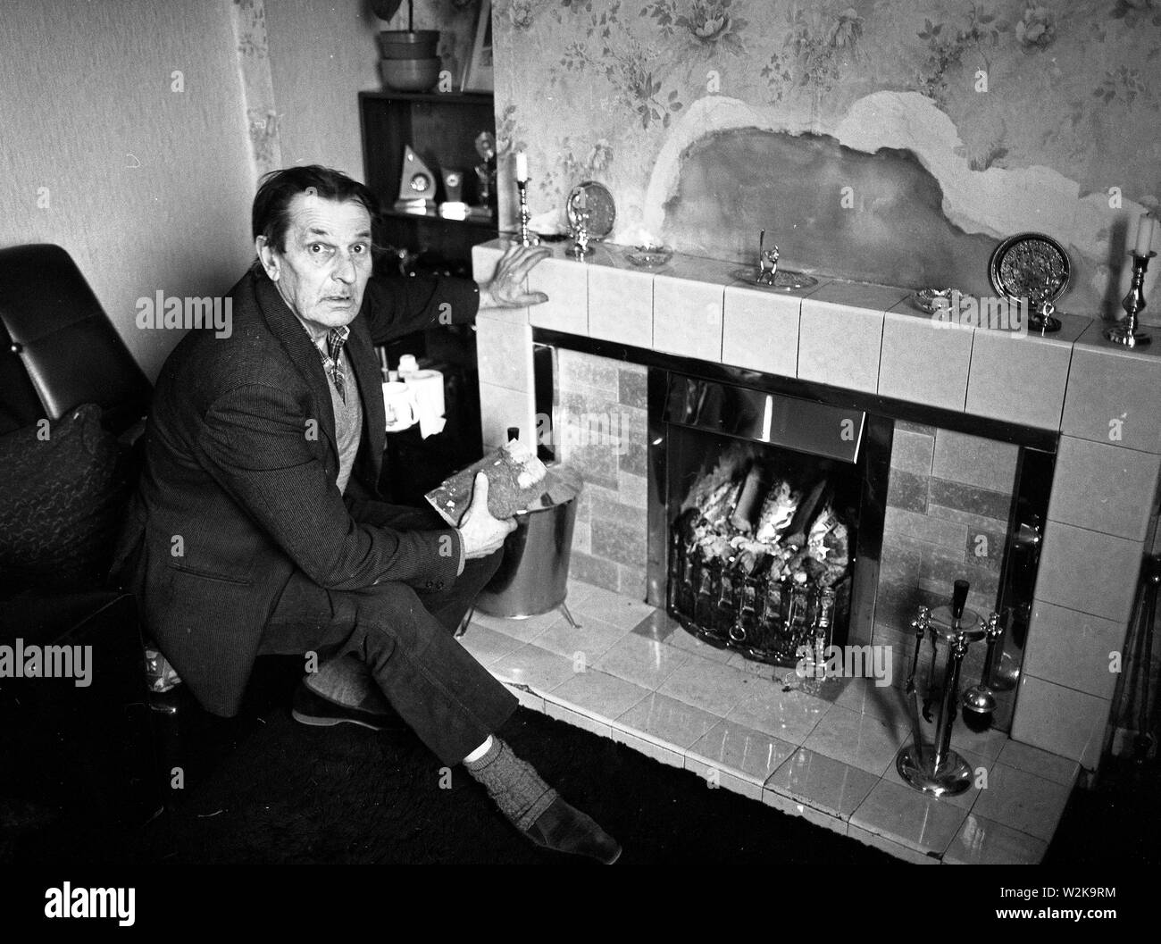 Uomo anziano che cerca di tenersi al caldo con un fuoco aperto nel North Yorkshire, Gran Bretagna 1985. bollette del carburante costi di riscaldamento rimborso carburante invernale Foto Stock