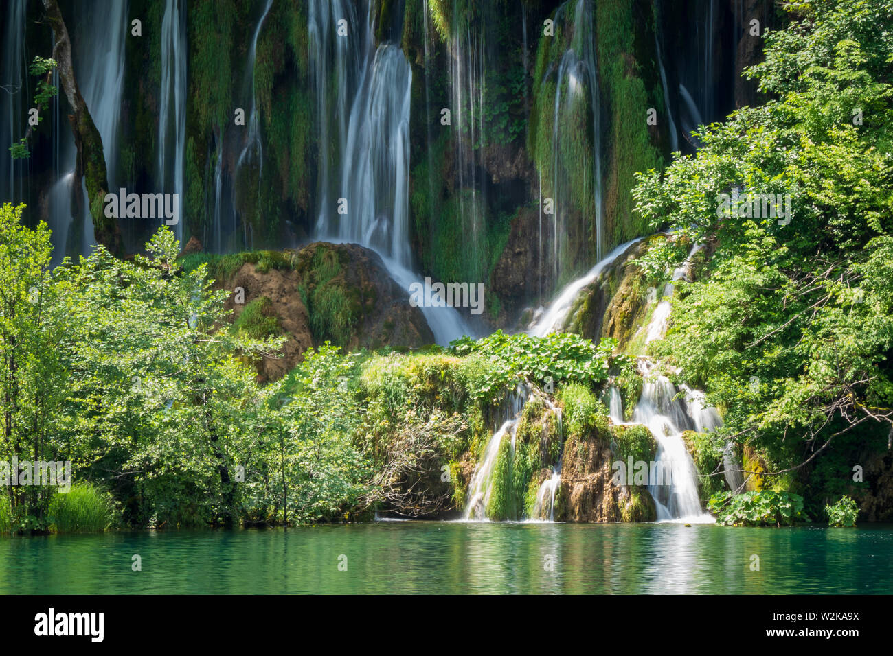 Crystal Clear, acqua pura e correre verso il basso le rocce di muschio in un bellissimo colore azzurro lago presso il Parco Nazionale dei Laghi di Plitvice, Plitvička Jezera, Croazia Foto Stock