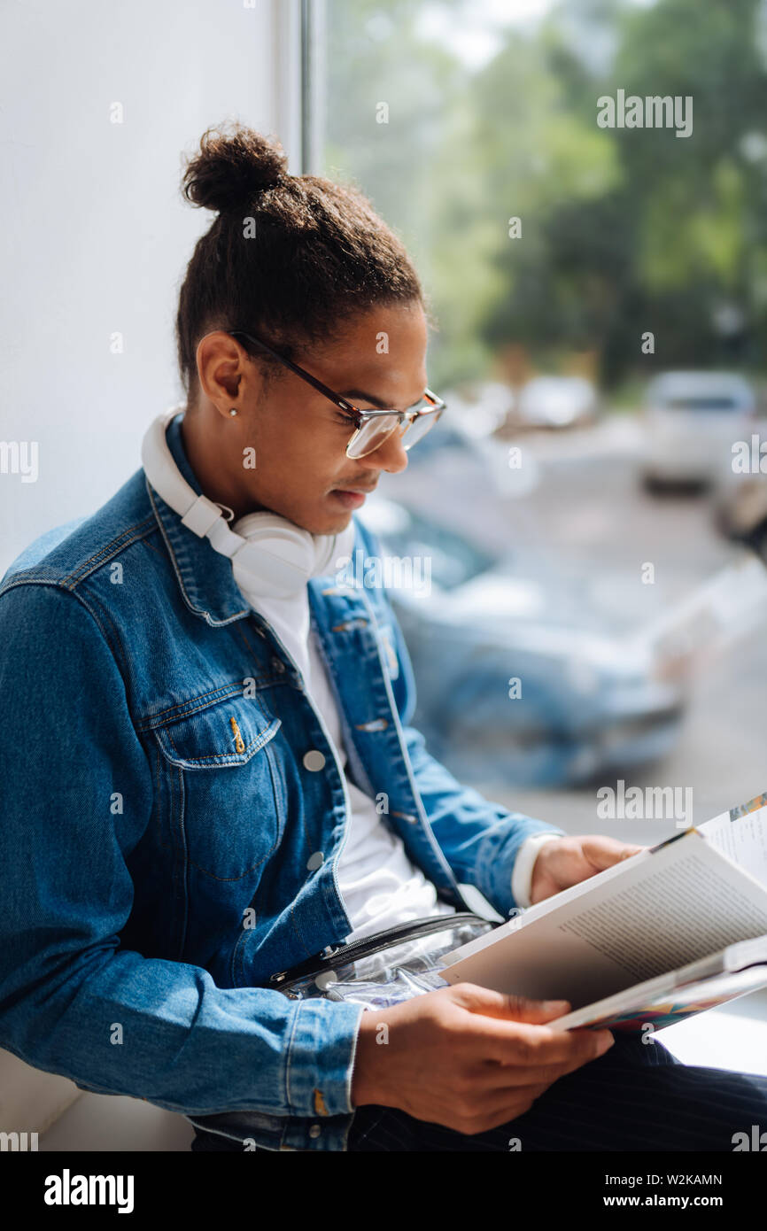 Interessante articolo. Tipo brunette uomo seduto sul davanzale e preparazione per testare la carta Foto Stock