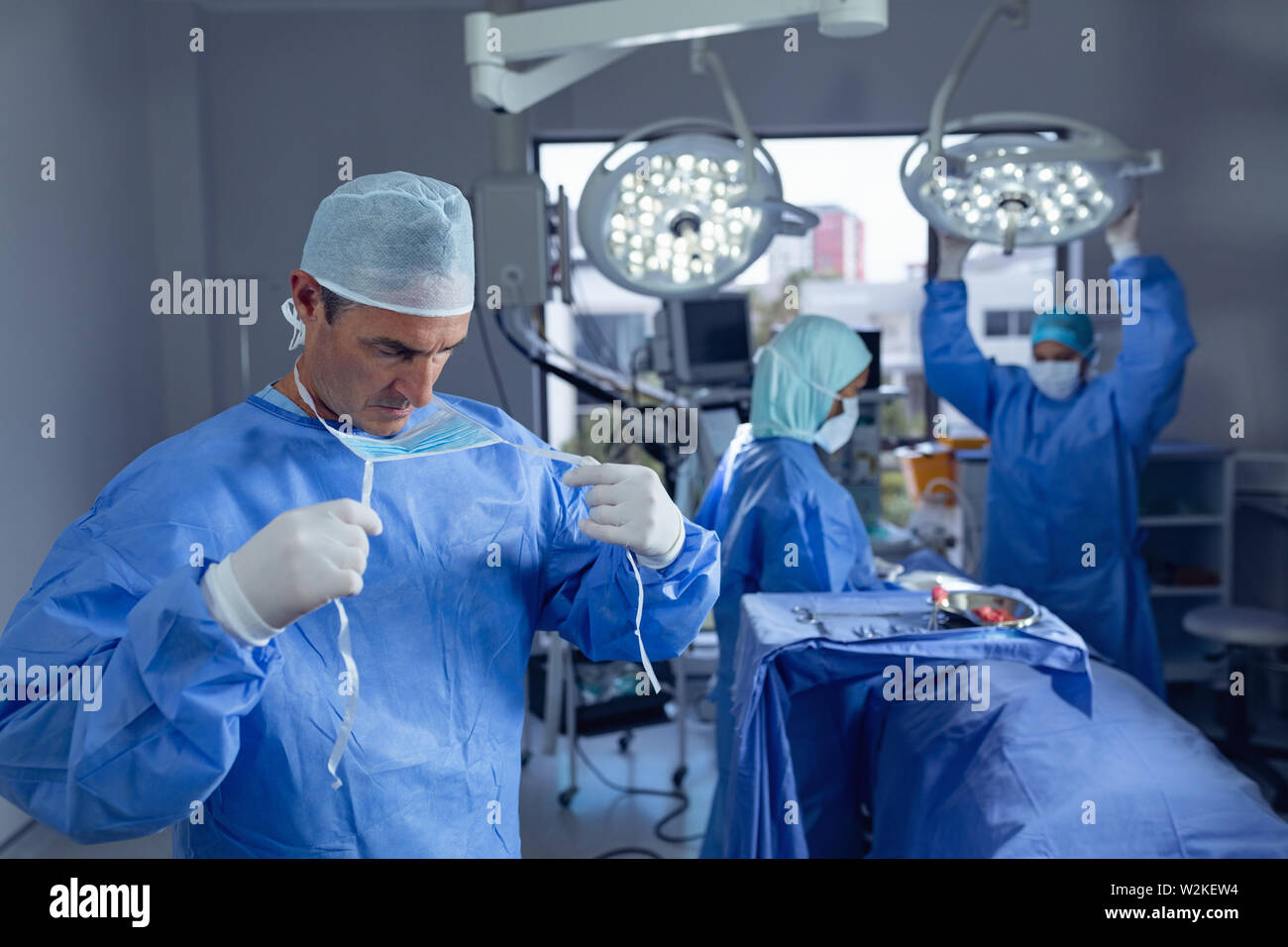 Chirurgo maschio indossando mascherina chirurgica in camera operativa all'ospedale Foto Stock