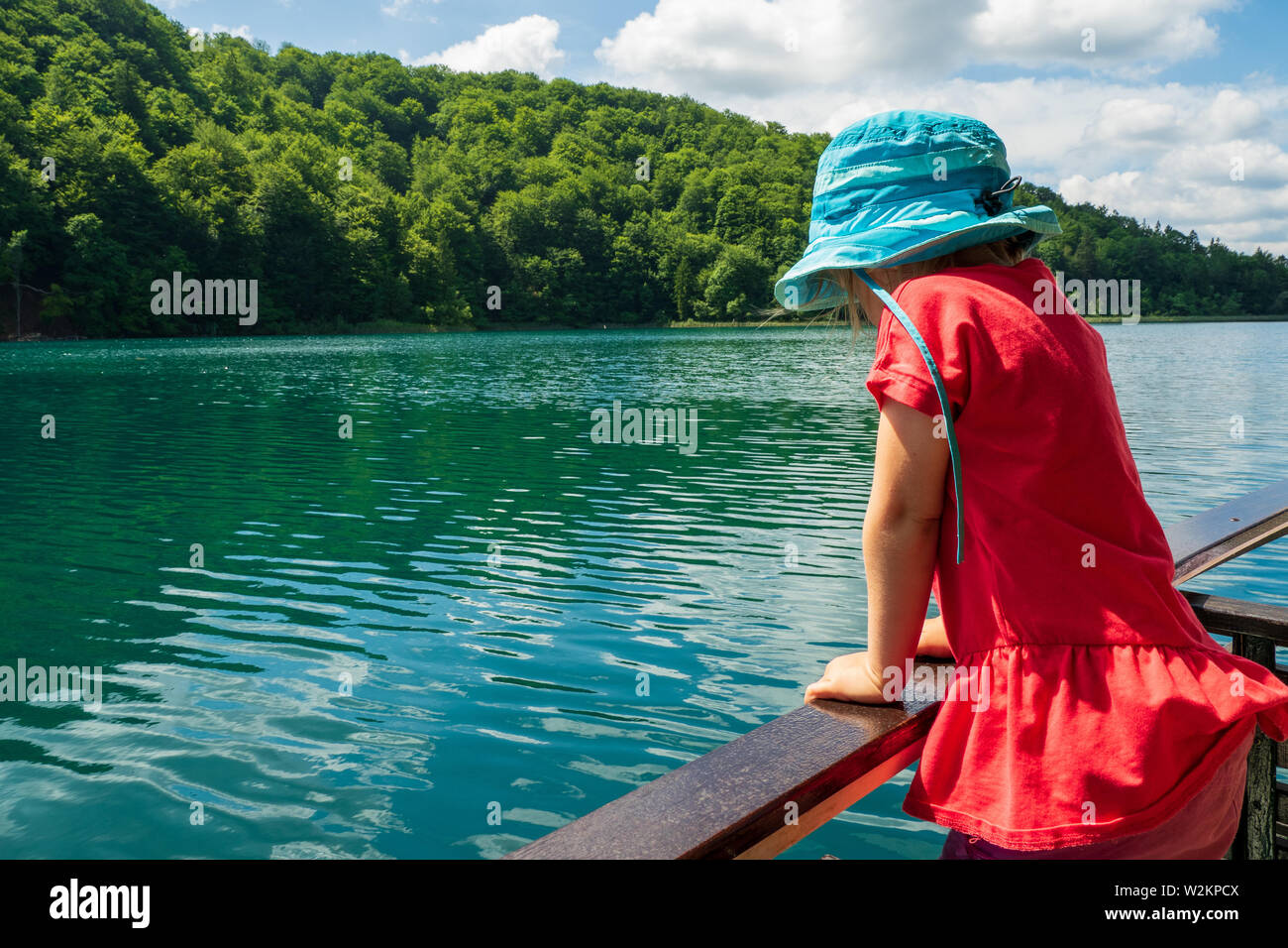 3 anno vecchia ragazza guardando sopra la ringhiera di un traghetto Crociera sul Lago Kozjak presso il Parco Nazionale dei Laghi di Plitvice, Plitvička Jezera, Croazia Foto Stock