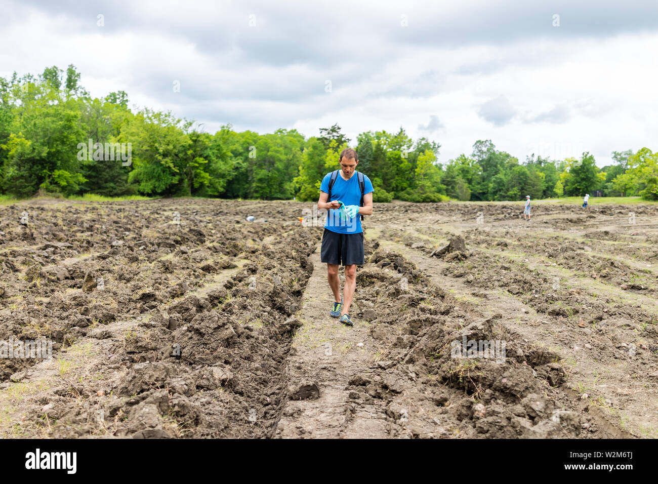 Il cratere di diamanti del parco statale con uomo che cammina alla ricerca di minerali di suolo marrone in Arkansas sporcizia paesaggio campo di prato Foto Stock