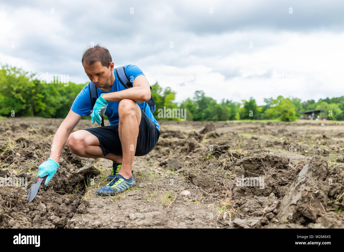 Uomo di scavare con la pala per pietre preziose di toccare il suolo marrone in Arkansas sporcizia paesaggio prato campo nel cratere dei diamanti è stato parco Foto Stock