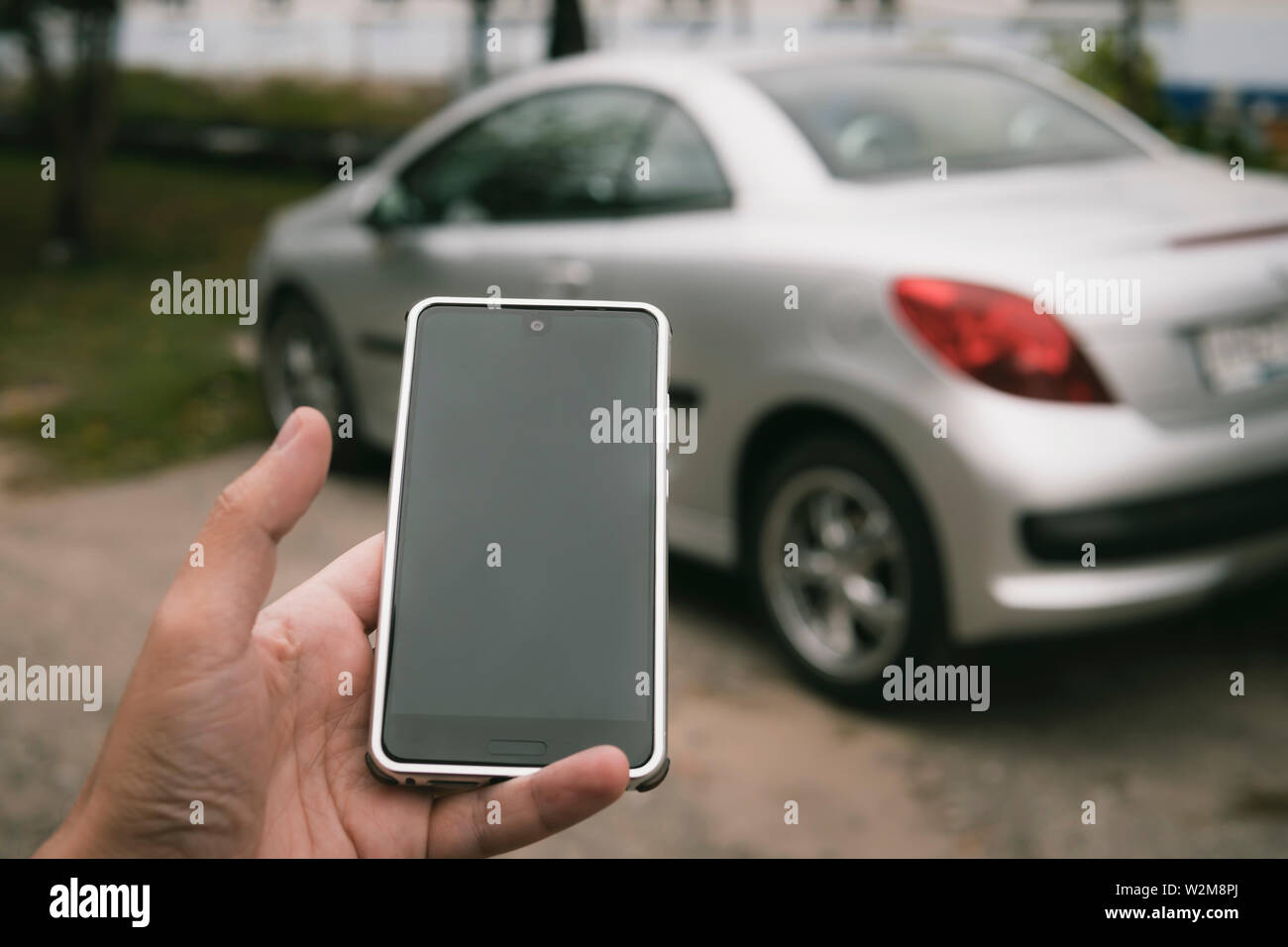 L'uomo utilizza mirrorlink sistema per integrare la sua vettura e lo smartphone. Applicazione auto viene eseguito su un telefono della persona. Conducente si sblocca il veicolo utilizzando gadget Foto Stock L'uomo utilizza mirrorlink sistema per integrare la sua vettura e lo smartphone. Applicazione auto viene eseguito su un telefono della persona. Conducente si sblocca il veicolo utilizzando gadget Foto Stock