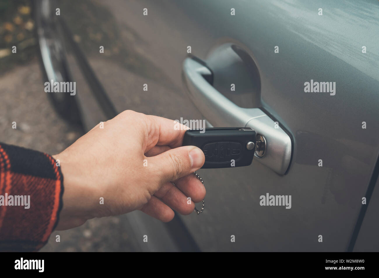 Close up di un maschio lato di apertura della porta auto. Persona inserisce il tasto del telecomando nel foro di serratura di un veicolo. Apertura della porta automatica utilizzando la chiave Foto Stock