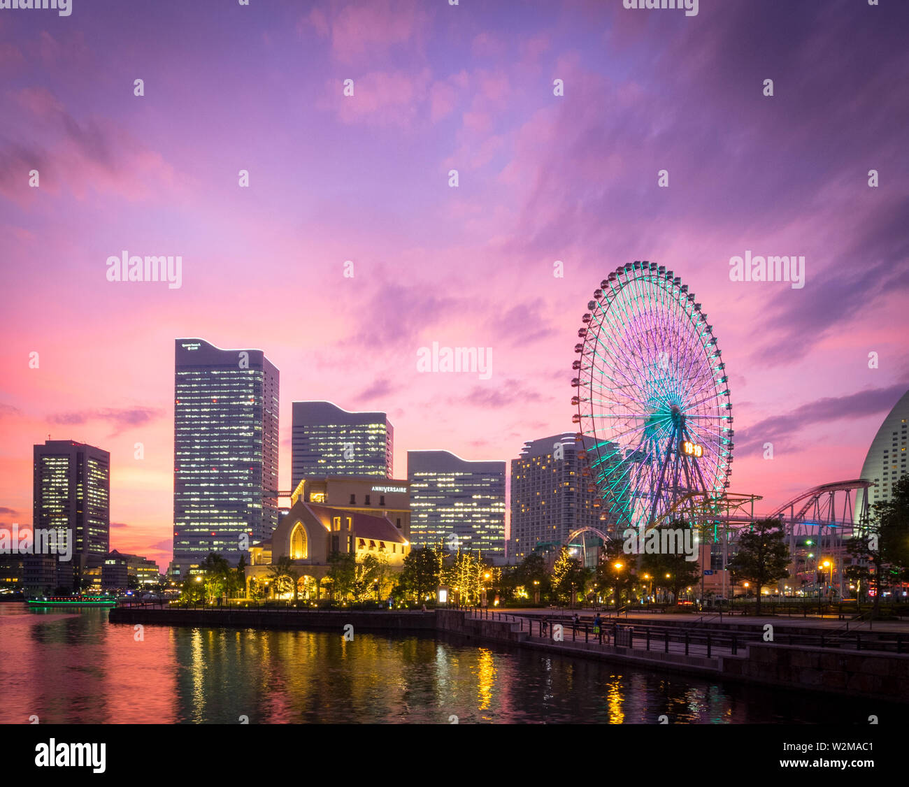 Una vista di una brillante tramonto sulla skyline di Yokohama a Minato-Mirai e il Cosmo orologio 21 ruota panoramica Ferris, come si vede da Unga Park. Yokohama, Giappone. Foto Stock