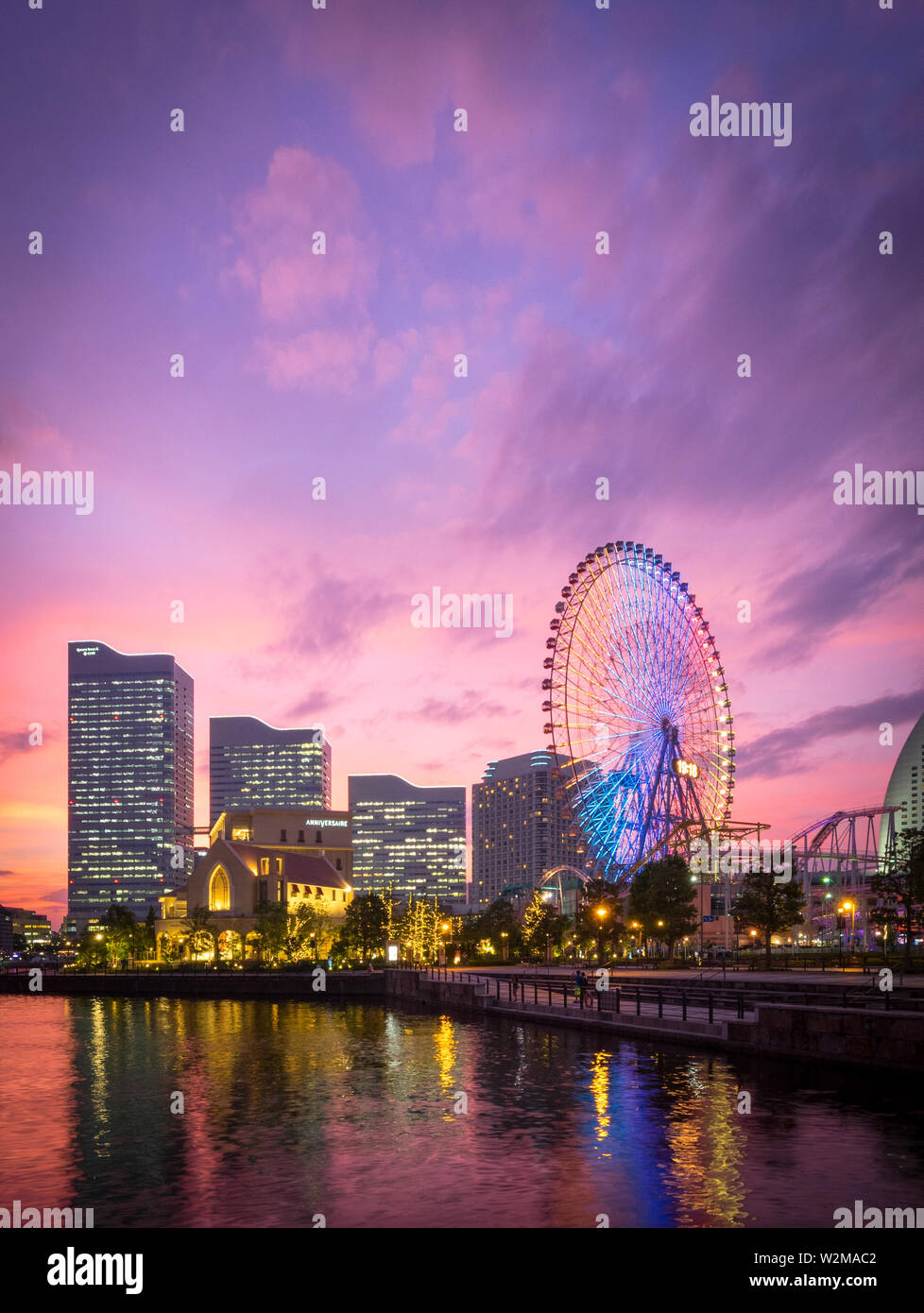 Una vista di una brillante tramonto sulla skyline di Yokohama a Minato-Mirai e il Cosmo orologio 21 ruota panoramica Ferris, come si vede da Unga Park. Yokohama, Giappone. Foto Stock