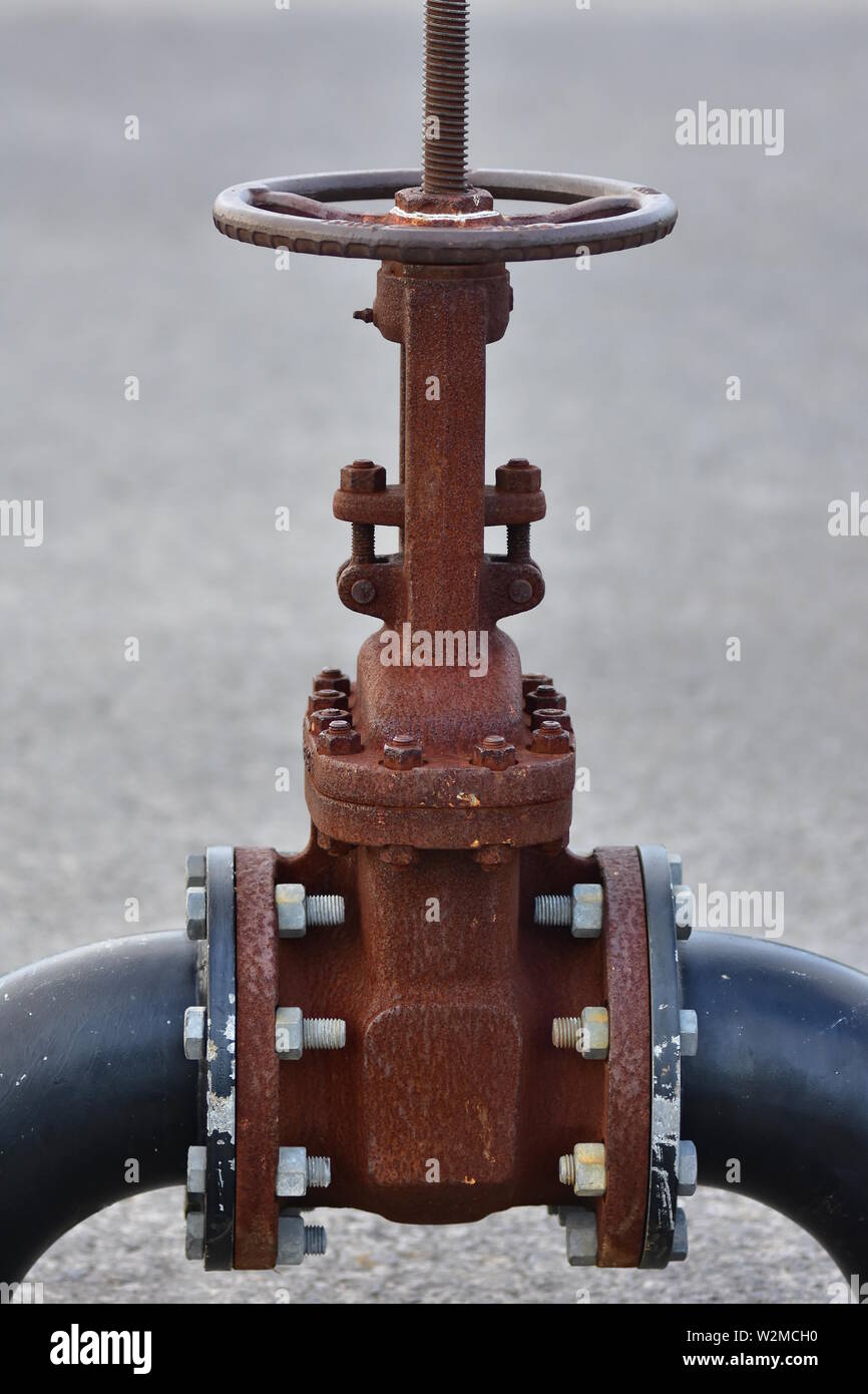 Enorme rusty industriale valvola ruota imbullonato al foro grande tubi. Foto Stock