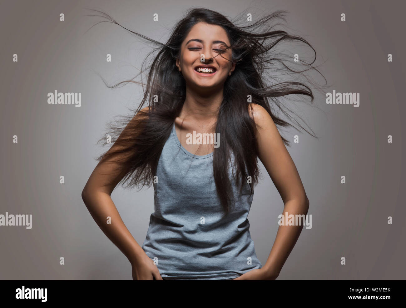 Giovane ragazza ridere con gli occhi chiusi e i capelli intorno battenti Foto Stock