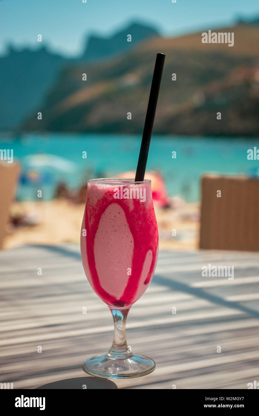 Rinfrescanti bevande congelate su un tavolino di un bar con il mare turchese e le montagne sullo sfondo Foto Stock