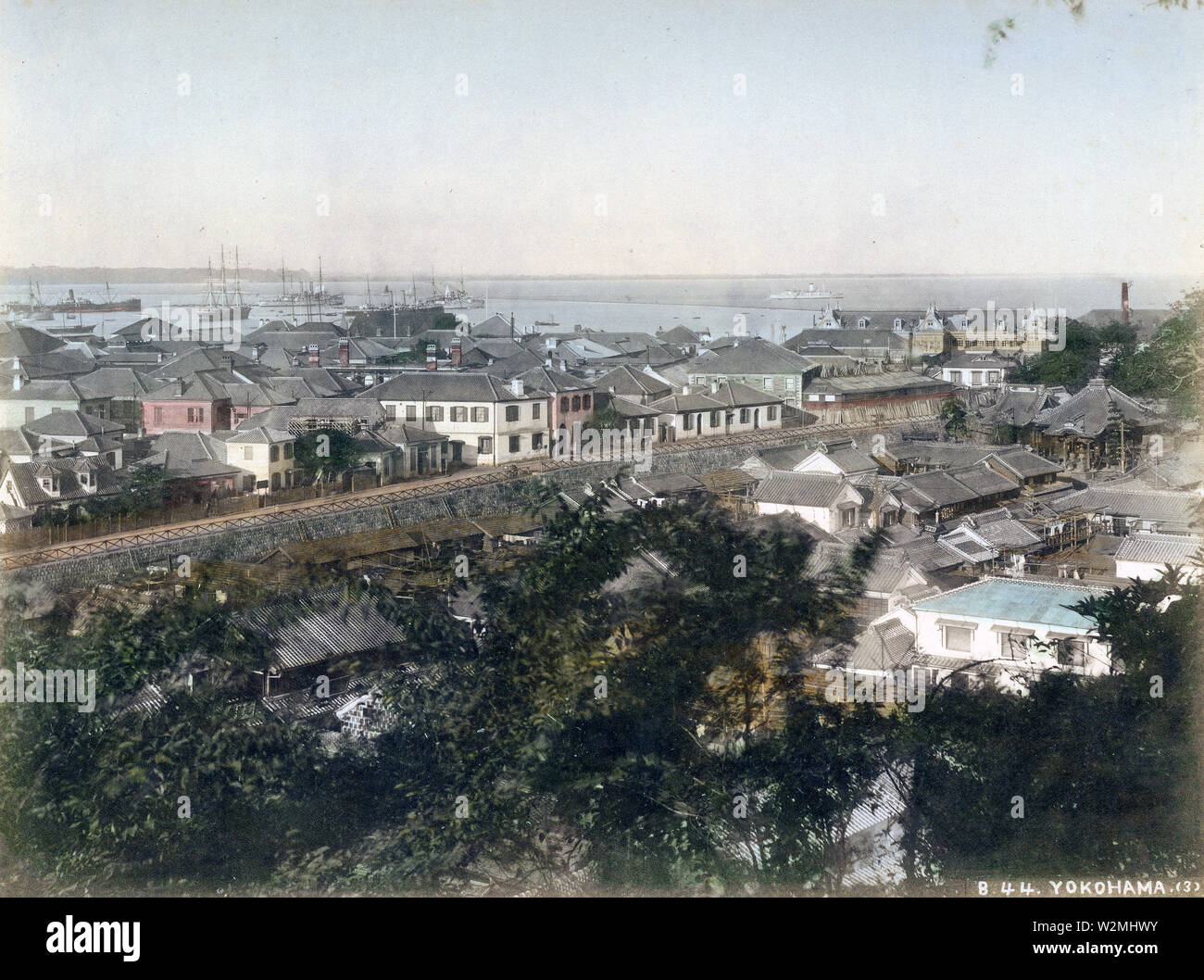 [ 1880 Giappone - Vista su Yokohama di liquidazione esteri ] - Vista sul Motomachi, Yokohama liquidazione esteri e il Porto di Yokohama da Motomachi Hyakudan a Sengenzaka a Yokohama, nella prefettura di Kanagawa qualche tempo in 1880. In primo piano è Motomachi dove gli originali abitanti del villaggio di Yokohama sono stati reinsediati. Zotokuin Tempio è visibile sulla destra. Sul lato opposto del canale Horikawa è il Yamashita insediamento. L'edificio di forma oblunga sulla costa è il Grand Hotel che è stato costruito nel 1887 (Meji 20). Xix secolo albume vintage fotografia. Foto Stock