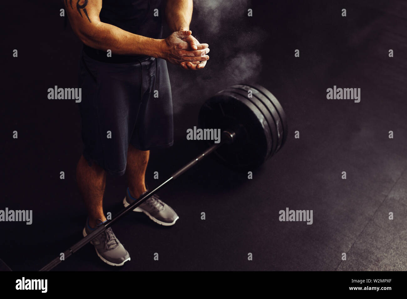 Atleta battendo le mani con talco prima deadlift barbells allenamento Foto Stock