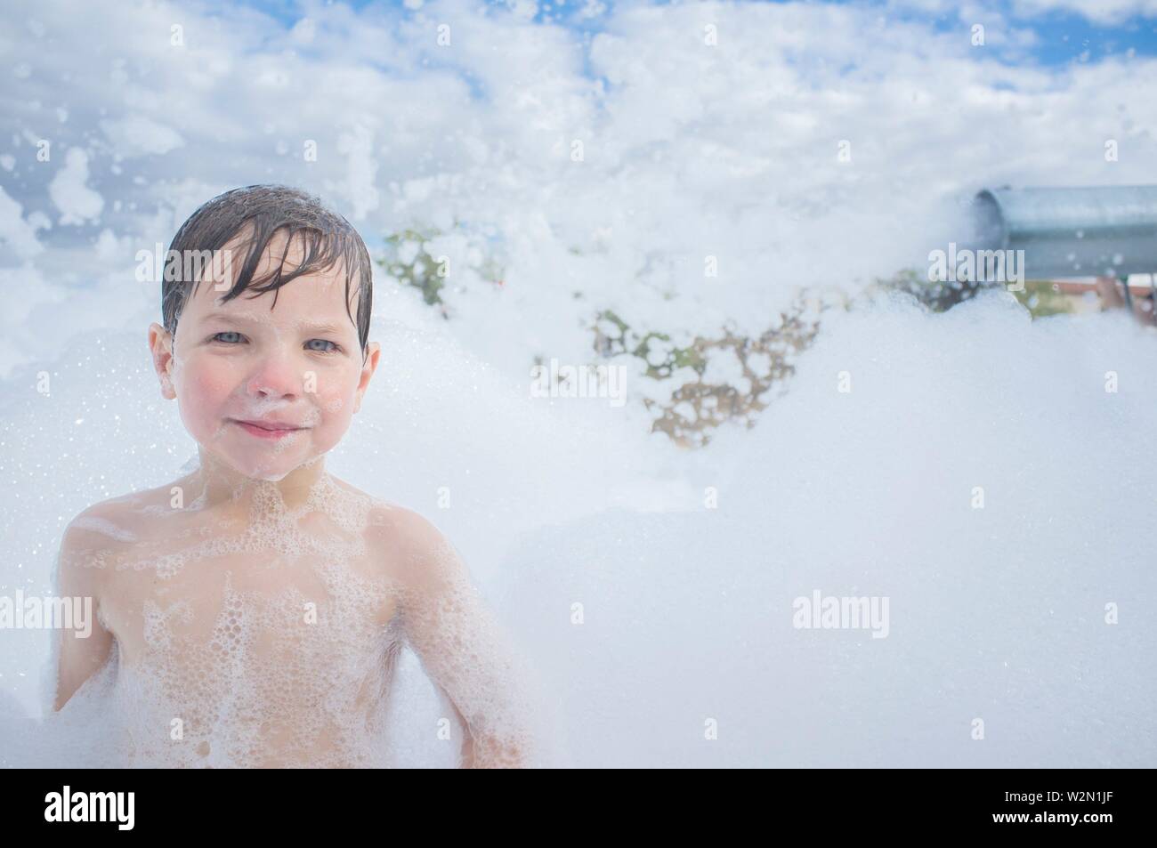 3 anni boy godendo al partito di schiuma all'esterno. Tempo libero attivo sulla stagione estiva per i bambini. Foto Stock