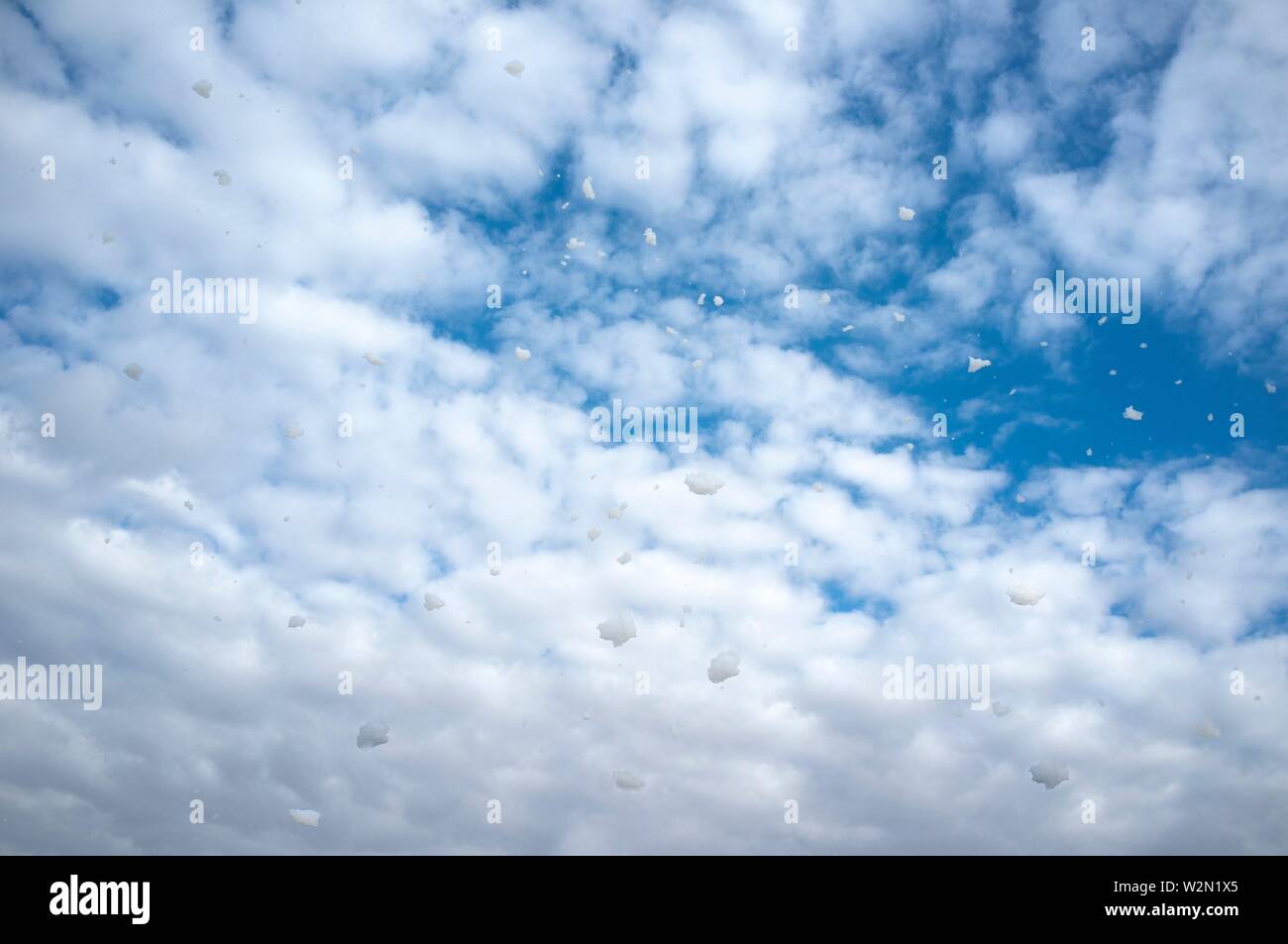 Cielo blu pieno di battenti pezzi di gomma espansa. Giornata di vento. Foto Stock