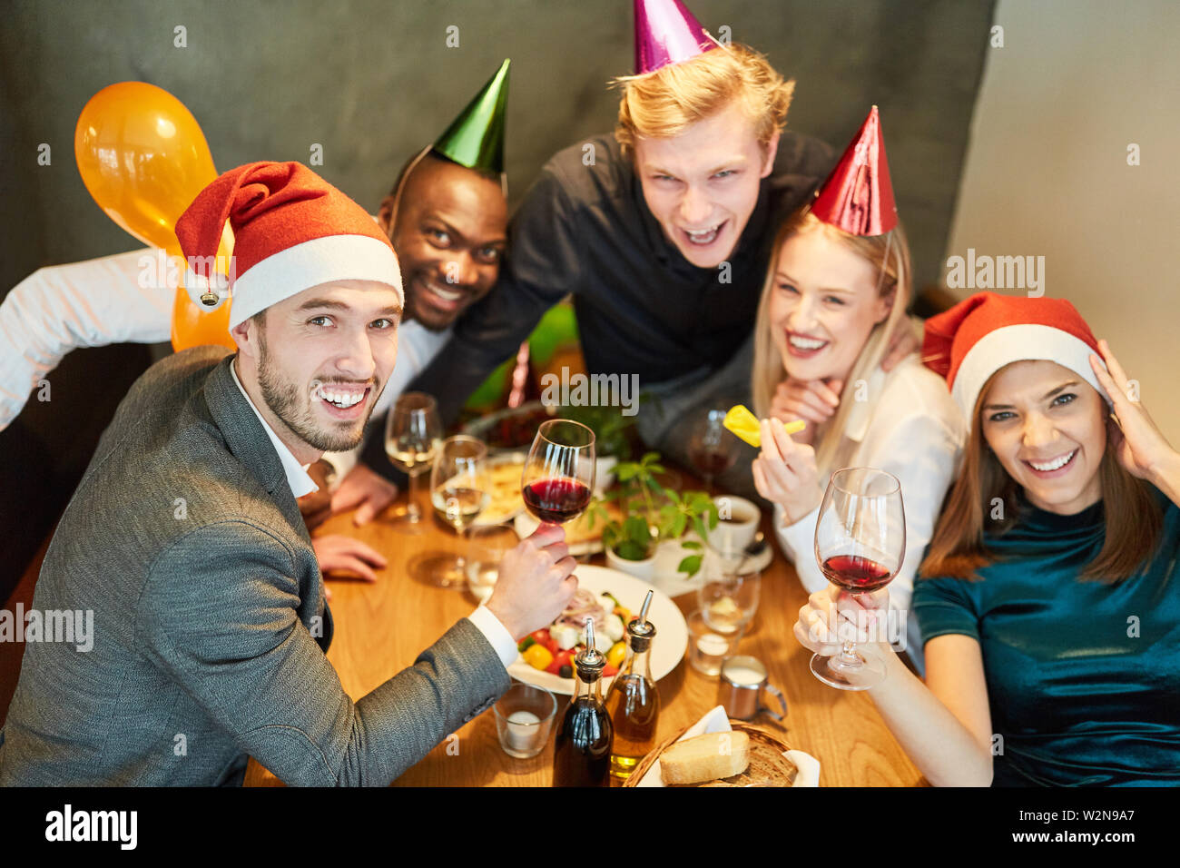 Gruppo di amici festeggia allegramente ad una festa di Natale presso il ristorante Foto Stock