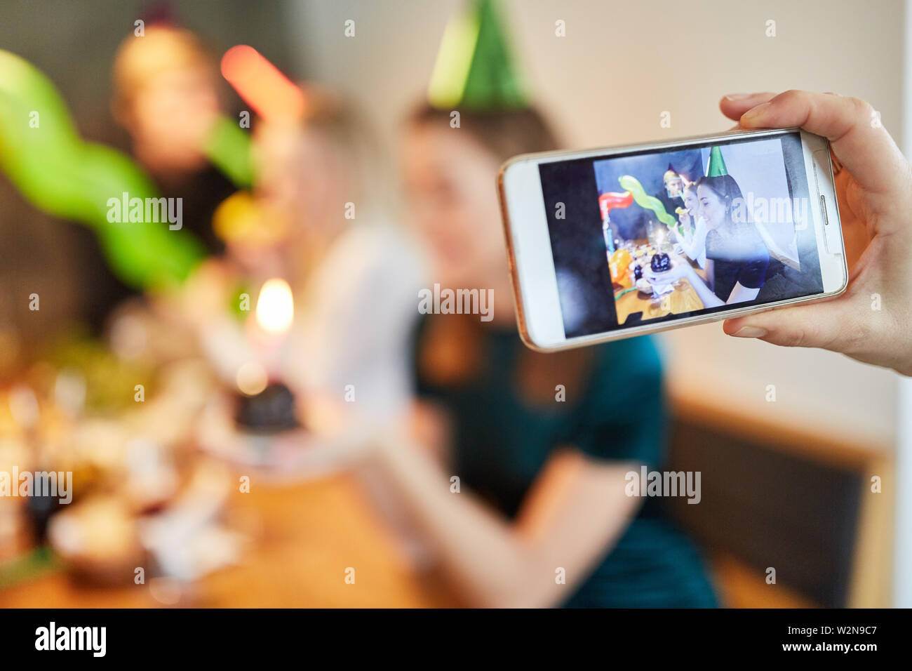 Mano su di una festa di compleanno mentre mangia una foto con lo smartphone Foto Stock