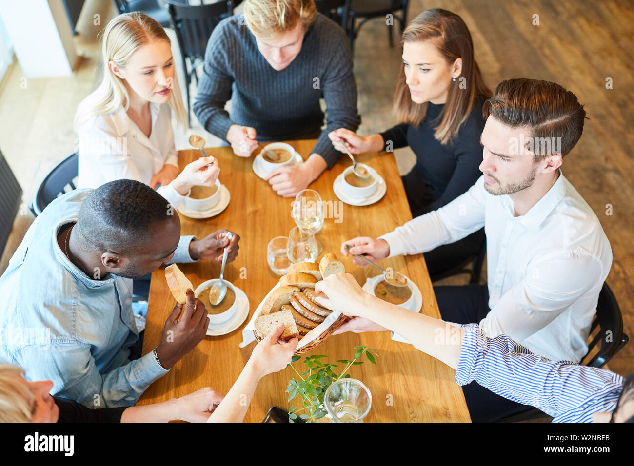 Un gruppo di giovani di mangiare la minestra come antipasto al ristorante Foto Stock