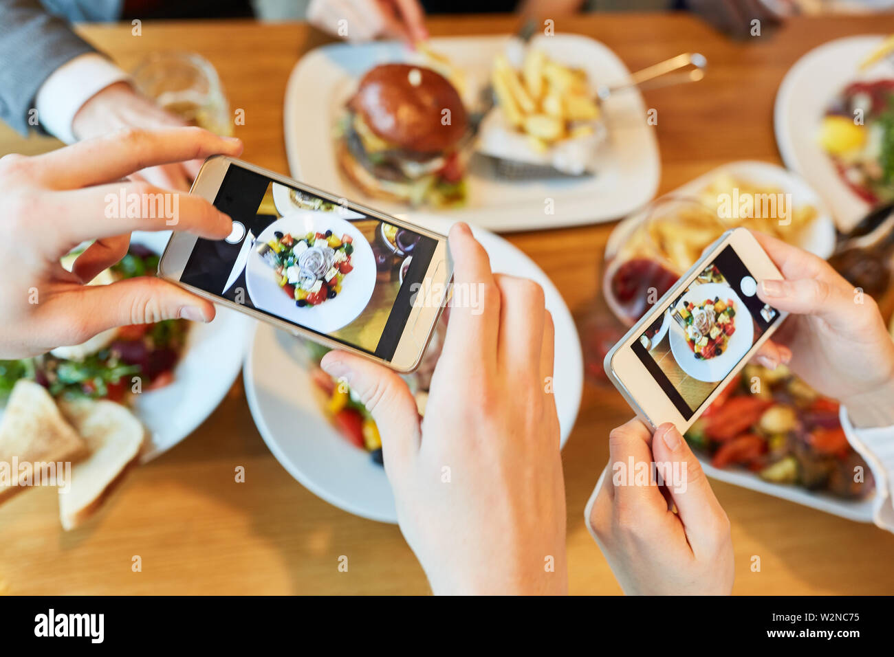 Le mani con gli smartphone fotografare il cibo sulla tavola in ristorante Foto Stock
