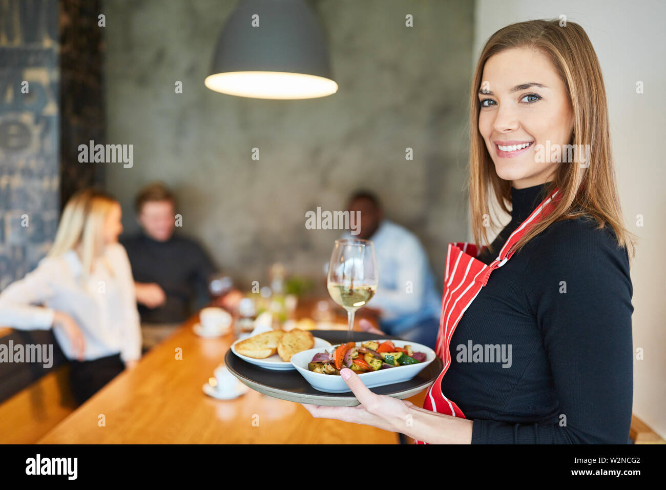 Giovane donna come un amichevole cameriera serve stuzzichini nel ristorante Foto Stock