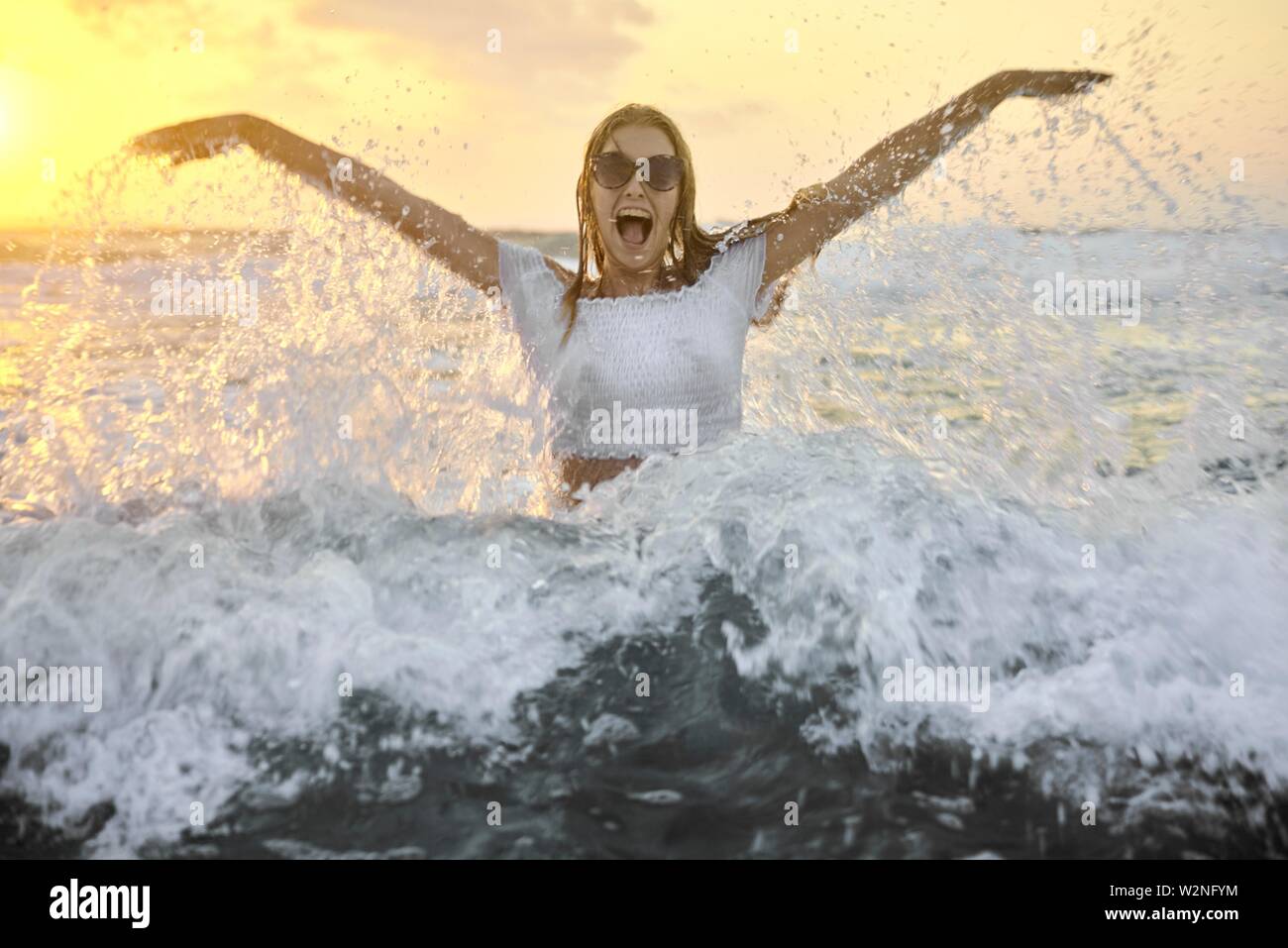Giovani vivace ragazza adolescente in acqua di mare nella spiaggia,  tramonto, vestiti bagnati, vacanze, acqua rinfrescante schizza in Creta,  Grecia Foto stock - Alamy