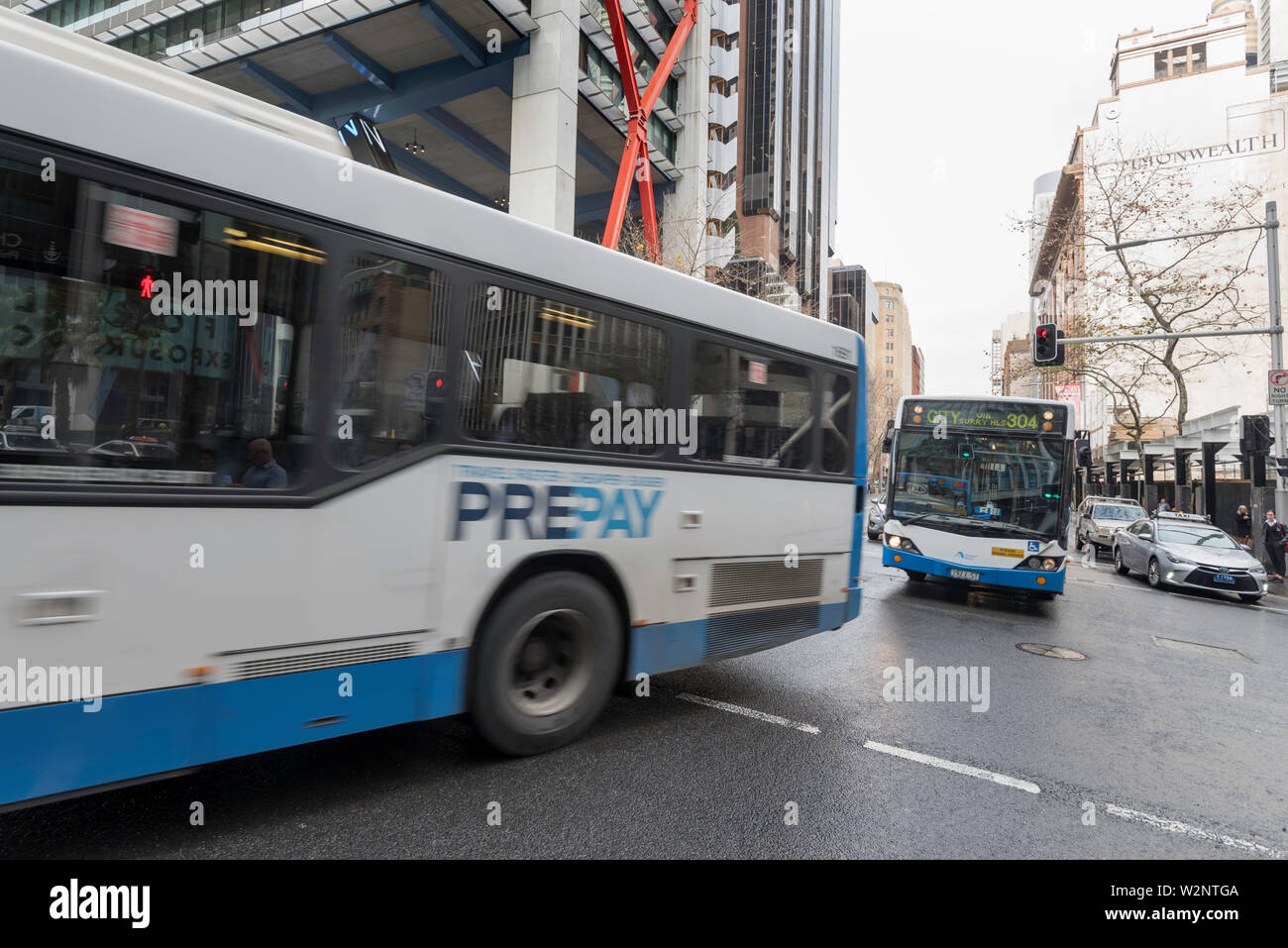 Due autobus di governo cross Hunter Street su Elizabeth Street su un inverno mattina ora di picco in Sydney Australia Foto Stock