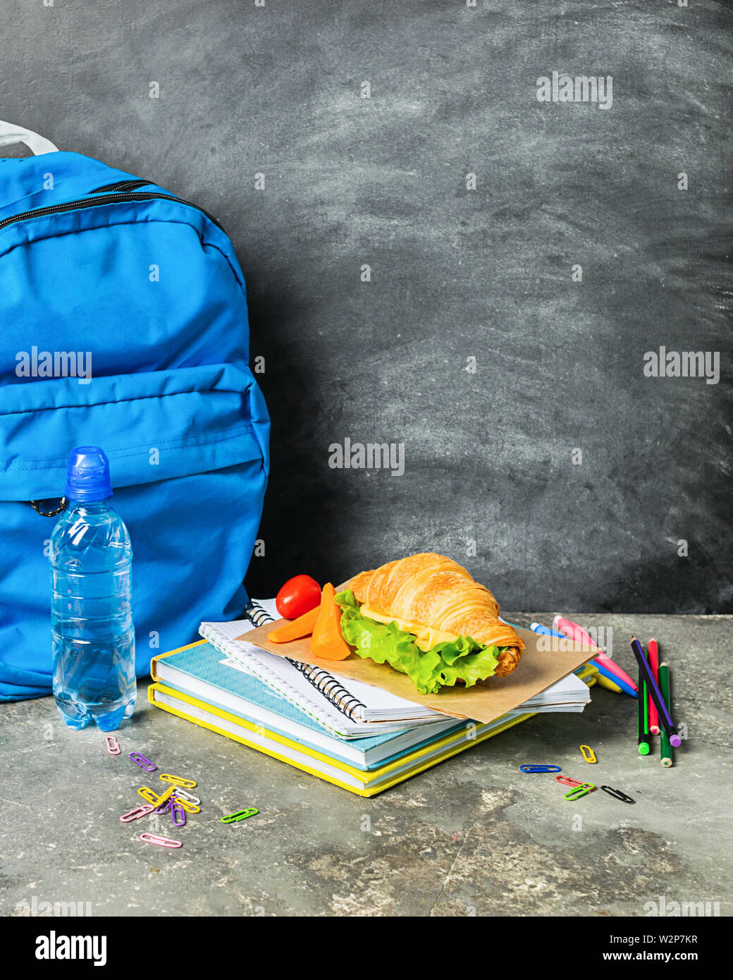 Sandwich fornisce formazione notebook zaino blu sullo sfondo di chalk board. Concetto torna a scuola. Foto Stock