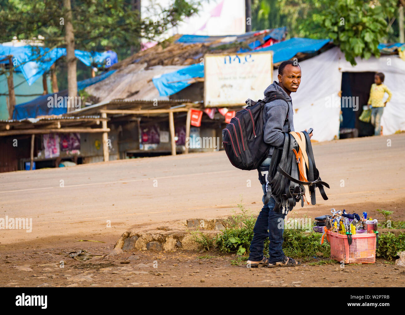 Giovane maschio commerciante vendita di merci dalla strada in Bonga, Etiopia Foto Stock