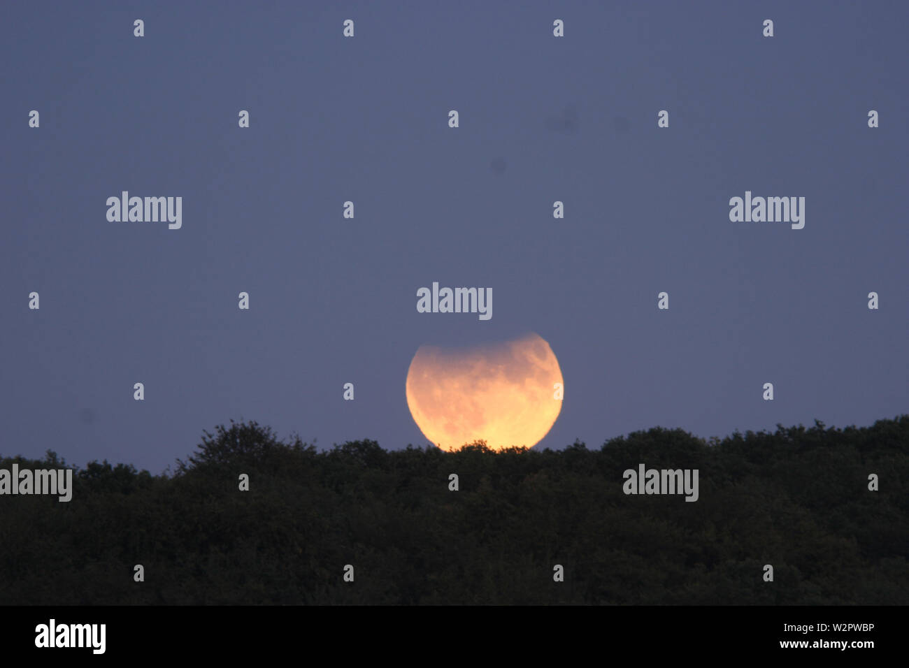 La luna crescente durante un eclissi parziale. La luna viene visualizzato in rosso in questa occasione a causa della sua bassa altitudine, e non a causa di eclipse. La parte superiore della luna di disco è coperta da terra ombra. Questa eclisse ha avuto luogo il 7 settembre 2006, ma un simile evento avviene come si vede dal Regno Unito il 16 luglio 2019, il cinquantesimo anniversario del lancio di Apollo 11. Foto Stock