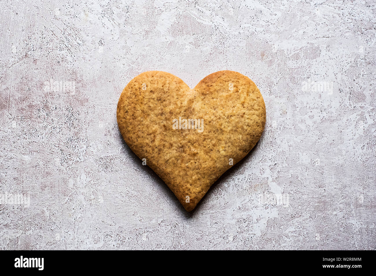 Angolo alto close up di uno appena sfornato hart biscotto a forma su sfondo grigio. Foto Stock