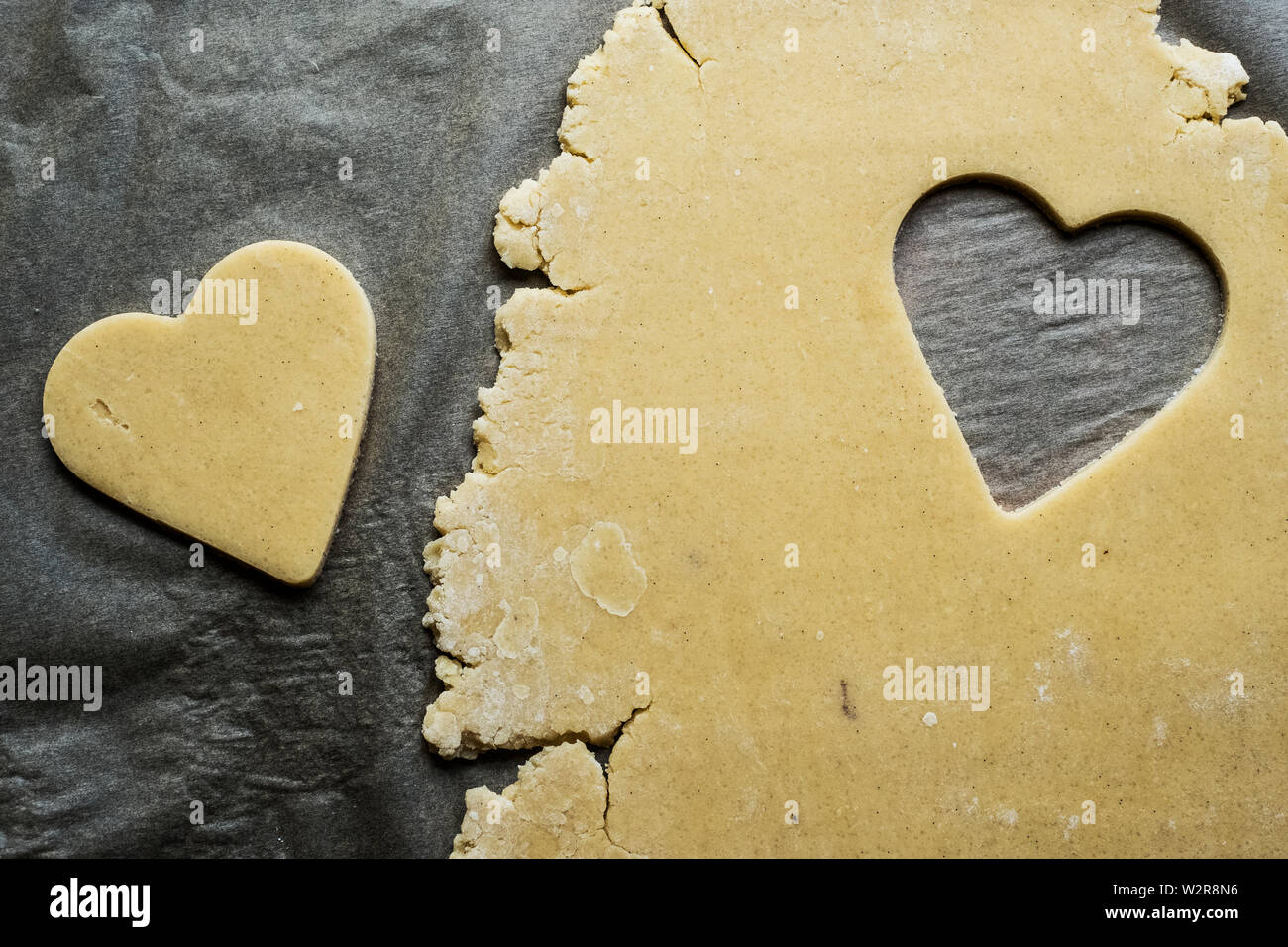 Angolo alto close up a forma di cuore i cookie tagliato fuori della pasta biscotto su sfondo grigio. Foto Stock