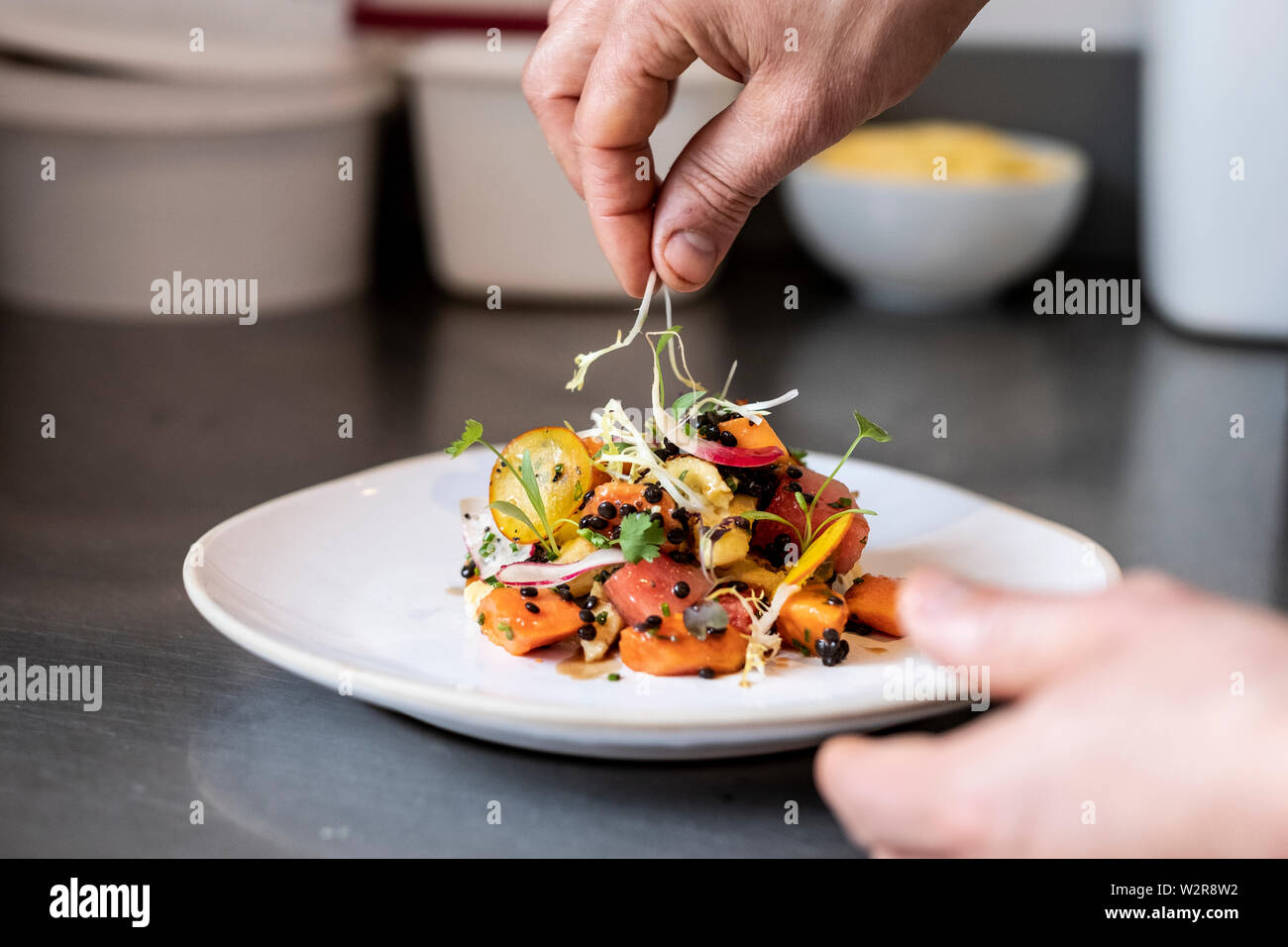 Close up di persona la piastra di farcitura di insalata con alcune erbe. Foto Stock