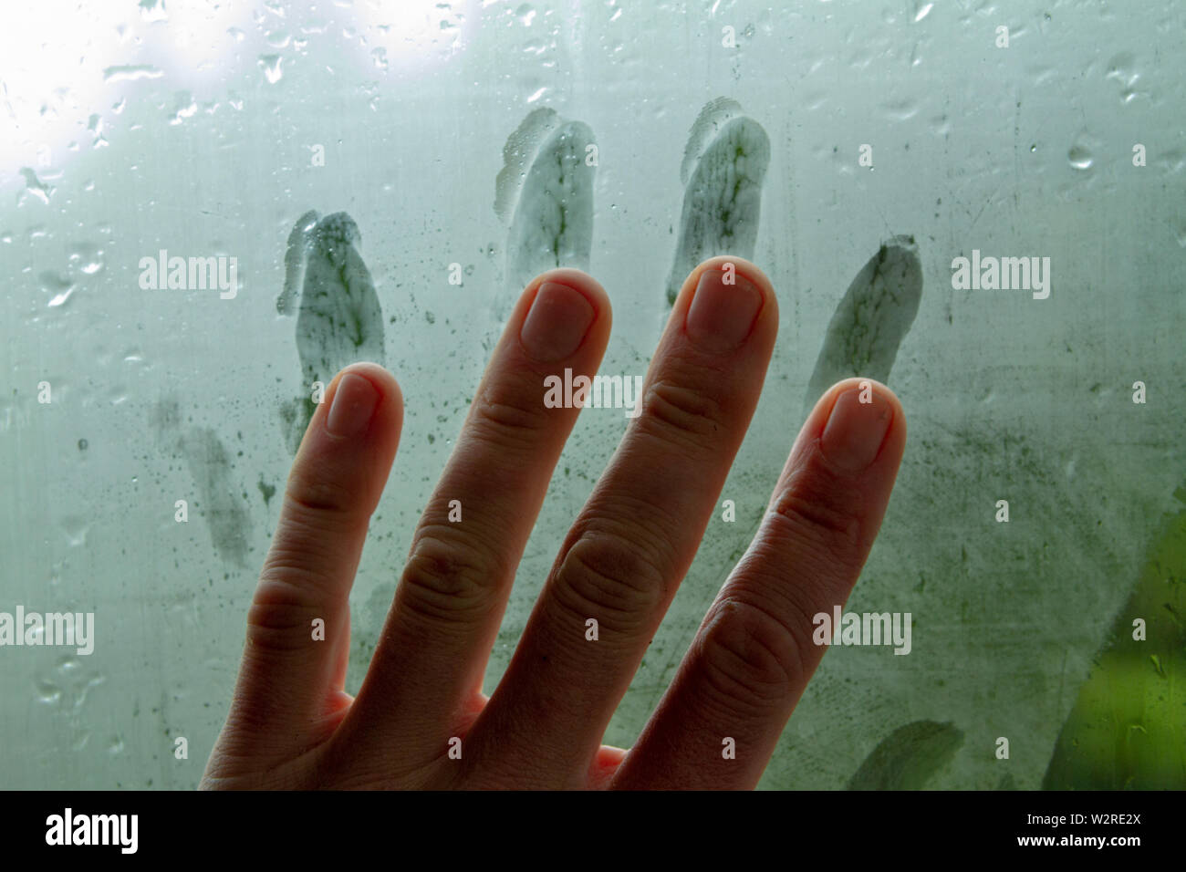 Voce maschile trascinando la sua mano e lasciando il dito striature su una finestra steamy in un umido auto. Foto Stock