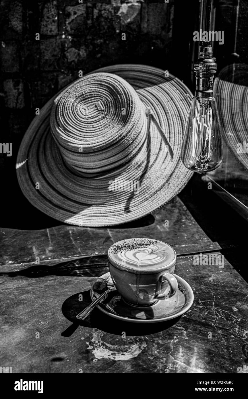 Una tazza di caffè cappuccino in una finestra soleggiata sulla giornata d'estate con cappello Foto Stock