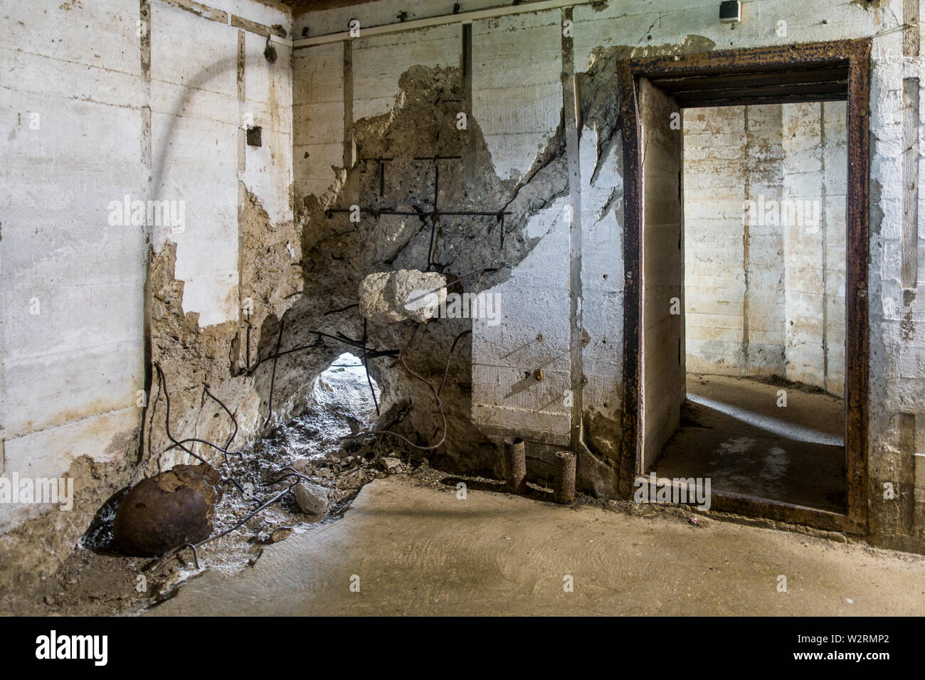 Guscio inesplose sono andato attraverso la parete del bunker in WWII Batterie d'Azeville / Batteria Azeville, parte del tedesco Atlantic Wall, Normandia, Francia Foto Stock