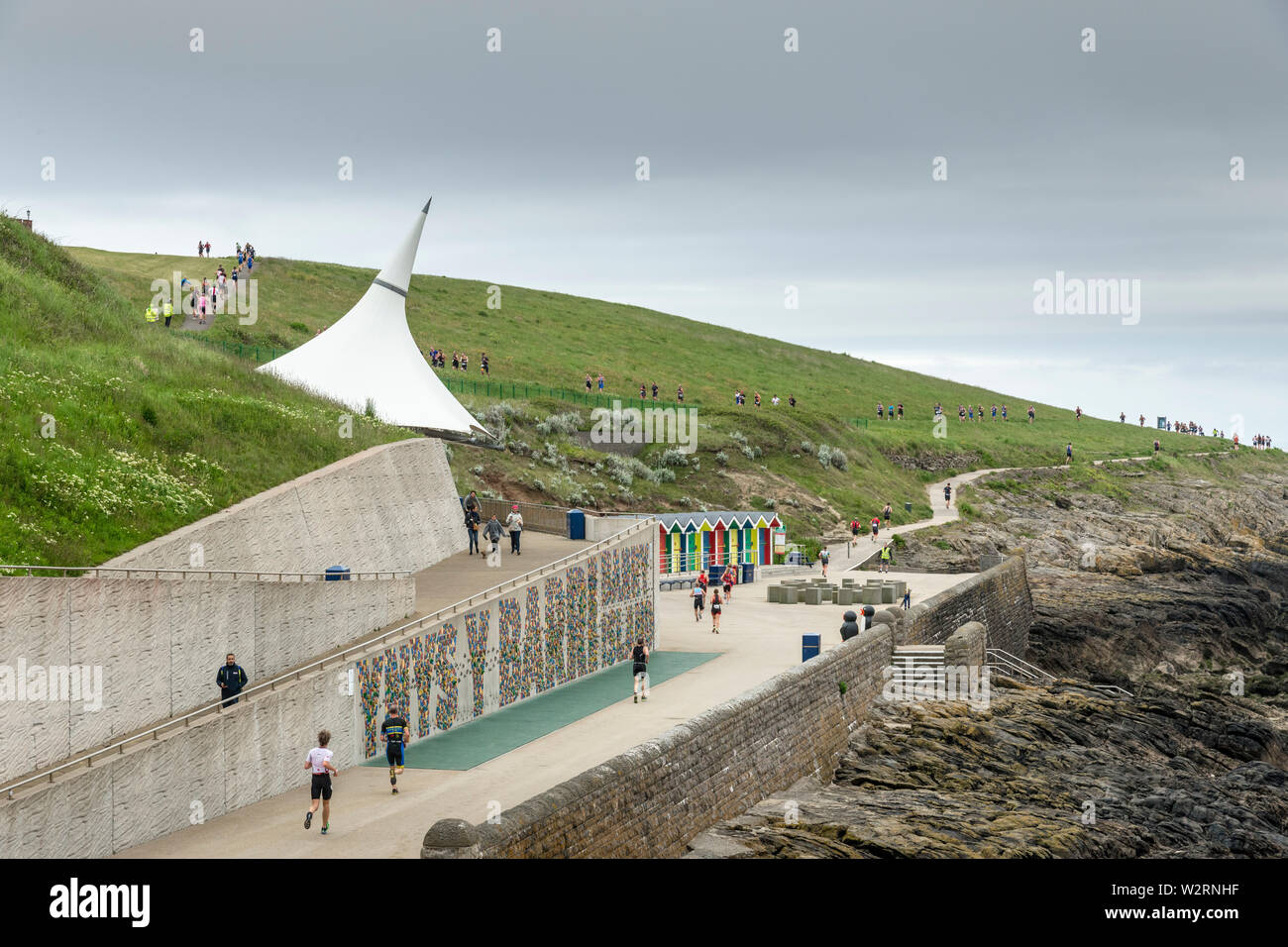 I concorrenti gestiscono lungo la passeggiata a mare e in tutta Nell's Point al 2019 Barry Island triathlon sprint su un nuvoloso giorno. Foto Stock