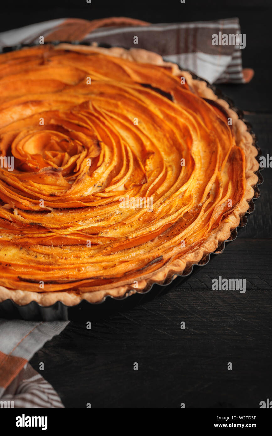 L'immagine verticale con patate dolci crostata in rose forma di fiore, su tavoli in legno nero. In autunno il cibo gustoso. Immagine rustico con American tart. Foto Stock