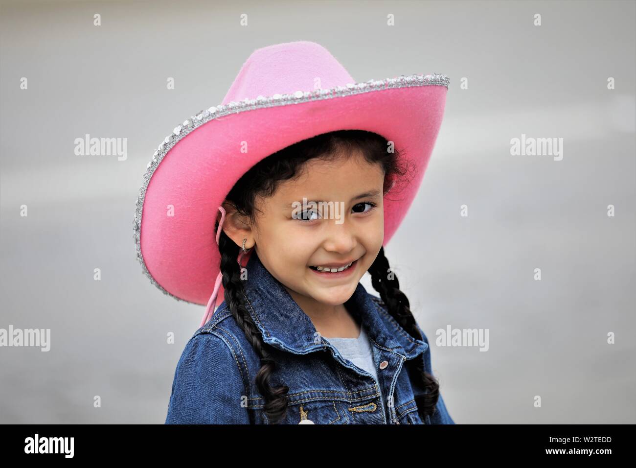 Real 5 anno vecchia ragazza ispanica a cowboy parade in California con cappello rosa e un sorriso Foto Stock