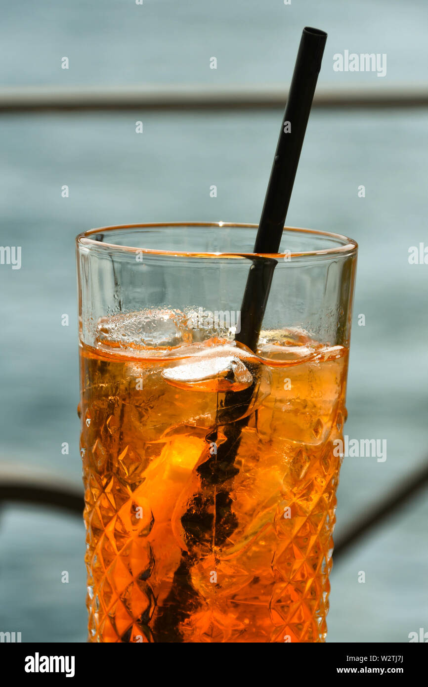 Vista ravvicinata di un bicchiere di Aperol Spritz su un tavolo con acqua in background. N. persone. Foto Stock