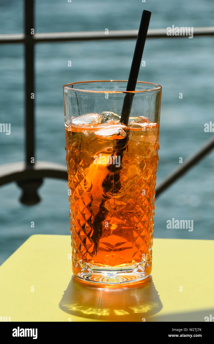 Vista ravvicinata di un bicchiere di Aperol Spritz su un tavolo con acqua in background. N. persone. Foto Stock