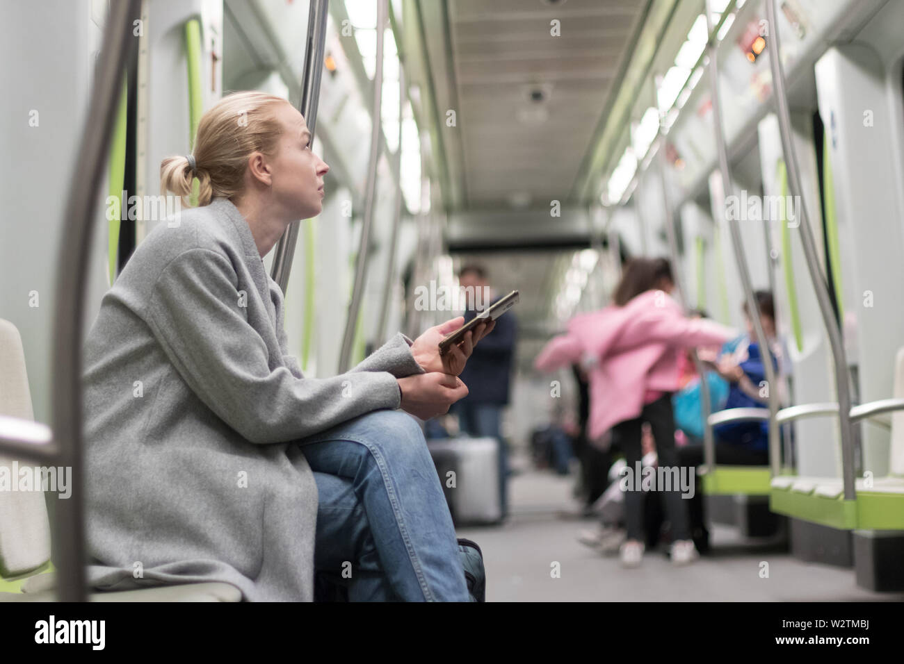 Bella donna bionda utilizzando smart phone durante il viaggio in metropolitana dei trasporti pubblici. Foto Stock