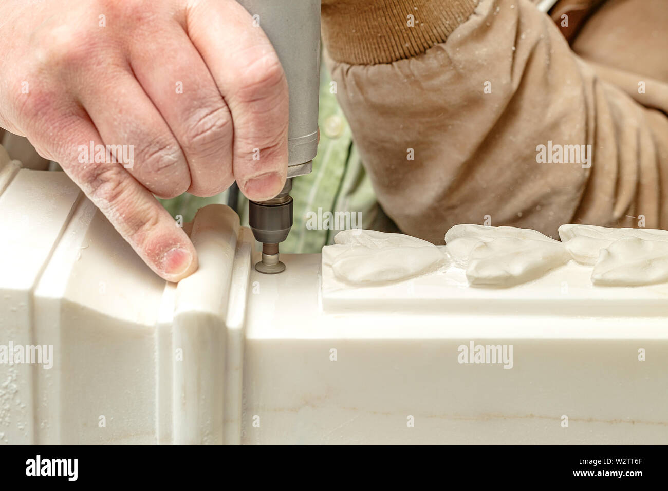 Mani scalpellatore close up. Elaborazione ART di una pietra. Piccolo trapano per lavori di artigianato Foto Stock