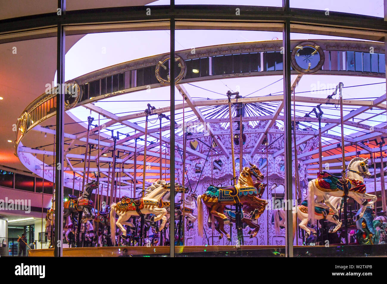 Un lavoratore spazza e si prepara a chiudere all'interno della giostra Looff con luci di lilla e cavalli vintage in Riverfront Park, Spokane, Washington. Foto Stock