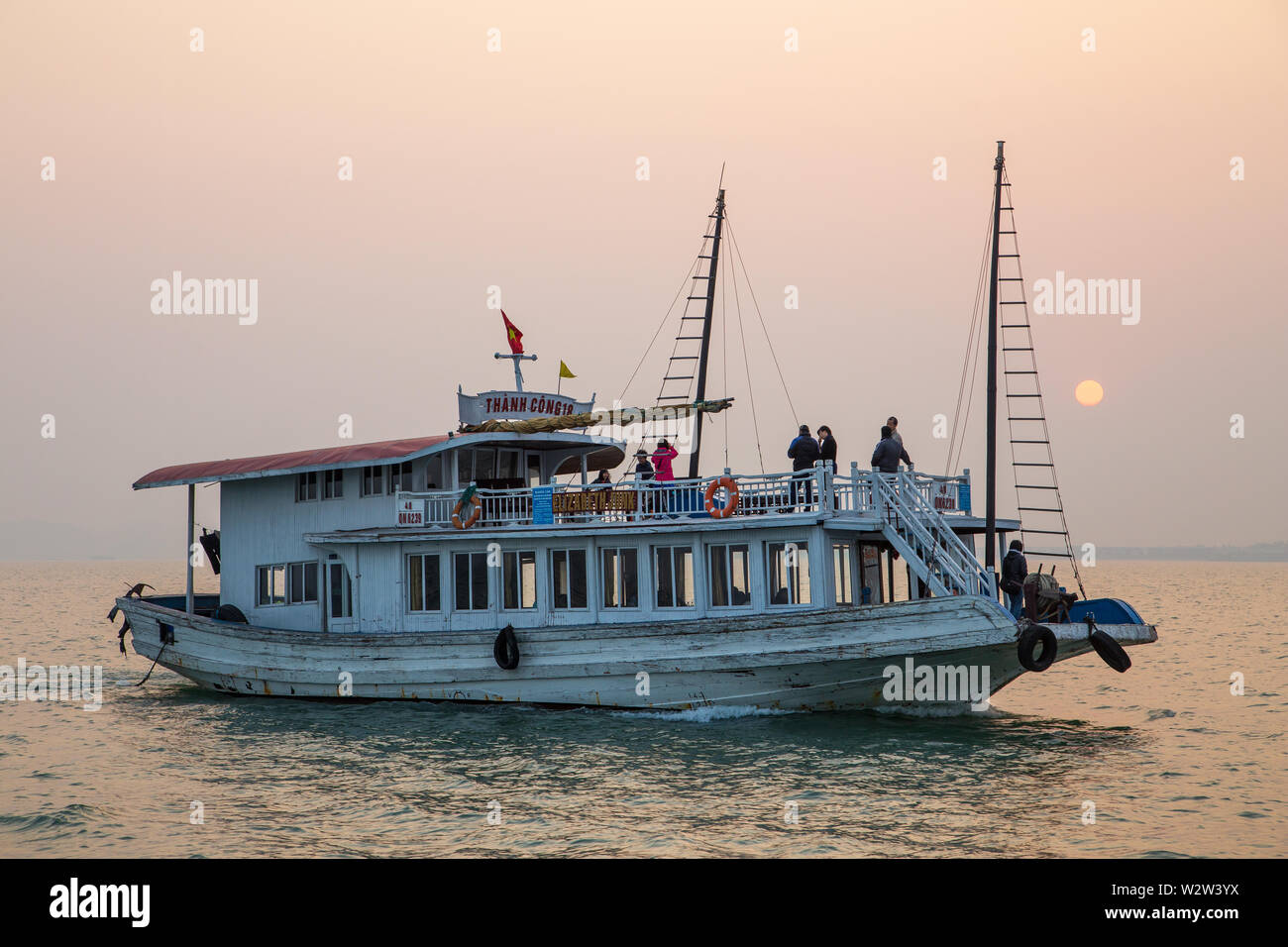 Halong Bay, Vietnam - Dicembre24, 2013: imbarcazione turistica la navigazione a Halong Bay con un paio di persone per quanto riguarda il tramonto. Foto Stock
