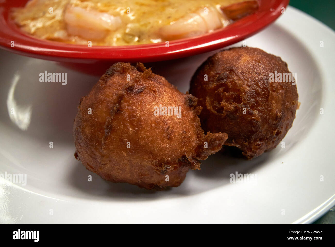 Due fritte hushpuppies come un lato serve accanto a una ciotola di gamberetti e di grits Florida USA Stati Uniti d'America Foto Stock